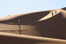 Quattro escursionisti percorrono una cresta di dune di sabbia finissima