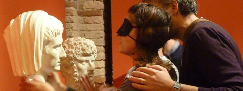 persona bendata esplora attraverso il tatto statue di teste
