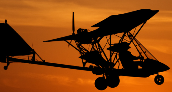 Aereo ultraleggero che vola al tramonto