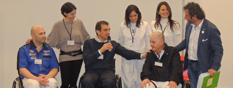 Gruppo di persone tra cui tre in sedia a rotelle parlano insieme durante una conferenza