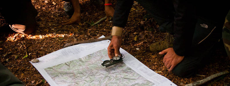 persone in un bosco con una cartina e una bussola