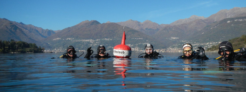 Gruppo di sub in acqua in procinto di immergersi nelle acque del lago